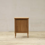 Wooden bathroom cabinet against a plain wall on a wooden floor