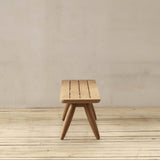 Wooden bench on a wooden floor with a plain wall background
