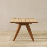 Wooden side table on a wooden deck with a beige wall background
