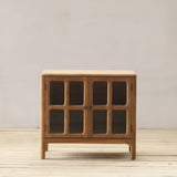 Wooden cabinet with framed glass doors on a wooden floor against a plain wall
