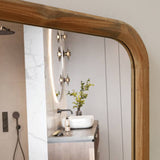 Wooden-framed mirror detail reflecting a sink and shower area.