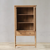 Wooden bookshelf with two drawers on a wooden floor against a gray wall