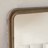 Large wooden-framed mirror on a wall with a neutral background