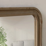 Reclaimed pine wood-framed mirror on a wall with a plant in the reflection
