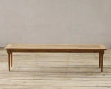 Wooden bench on a wooden floor with a plain wall background