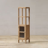 Tall wooden bathroom cabinet with glass panels on a wooden floor against a plain wall.