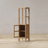 Wooden bathroom cabinet with a glass door on a wooden floor against a plain wall