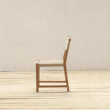 Wooden chair on a wooden floor with a plain white wall background