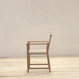 Wooden armchair on a wooden floor with a plain white wall background