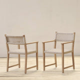 Two wooden armchairs with woven backrests on a wooden floor against a plain wall.
