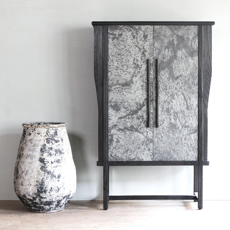 LUNAR Stone Veneer Tall Cabinet with grey stone next to a big vase.