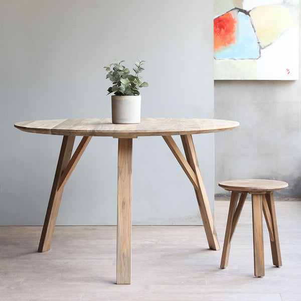 Xie Indoor Round Dining Table with a potted plant on top of it paired with Xie Indoor Stool.