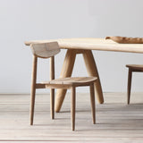 Wooden dining table and chairs on a light wooden floor with a white wall background