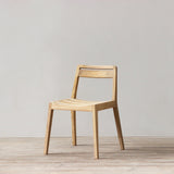 Wooden chair on a wooden floor with a plain white wall background