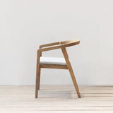 Outdoor dining chair with cushion on a wooden floor against a plain wall