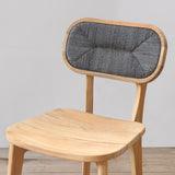 Outdoor wooden chair with rattan backrest on a wooden floor against a plain wall