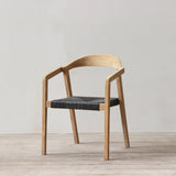 Outdoor rattan woven dining chair on a wooden floor against a plain wall