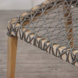 Close-up of a woven chair seat with wooden frame on a wooden floor.