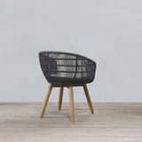 Rattan chair with wooden legs on a wooden floor against a light gray wall