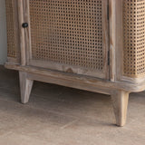 Wooden cabinet with rattan doors on a wooden floor.