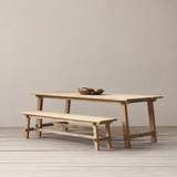 Outdoor wooden dining and bench set on a wooden floor against a plain wall