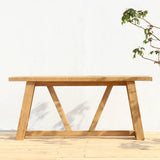 An outdoor console table on a wooden floor and a plain background.