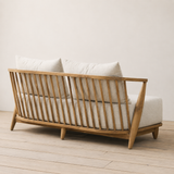 Sofa with wooden frame and white cushions on a light wooden floor.