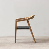 Outdoor rattan woven dining chair on a wooden floor against a plain wall