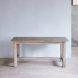 Reclaimed pine wood table in a minimalistic room with a light gray wall and wooden floor.