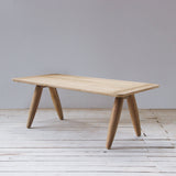Wooden table on a wooden floor with a plain white wall background
