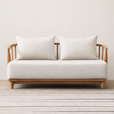 Sofa with wooden frame and white cushions on a wooden floor.