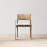 Outdoor wooden armchair with a white cushion on a wooden floor and light gray wall
