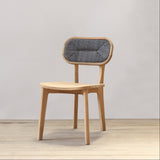 Outdoor wooden chair with rattan backrest on a wooden floor against a plain wall
