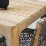 Wooden dining table with slatted top and rope chair.