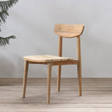 Wooden chair in a minimalistic room with a plant and wooden floor.