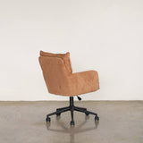 Brick-orange office chair with wheels on a light wooden floor and white wall background
