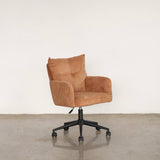 Upholstery chair with wheels on a stone floor against a grey wall.