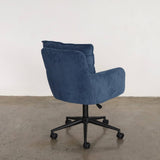 Blue office chair with wheels on a stone floor against a white wall