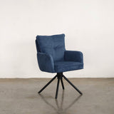 Blue upholstered dining chair on a stone floor against a white wall