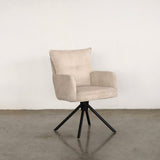 Beige upholstered dining chair on a stone floor against a plain wall