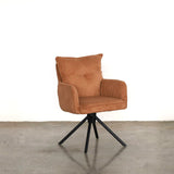 Orange upholstered dining chair on a stone floor against a plain wall