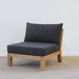 Modern outdoor sofa with dark gray cushion and wooden frame on a light wooden floor.
