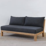 Gray sofa with wooden frame on a light wooden floor and white wall background