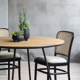 Circular dining table paired with Moi Dining chairs with tan fabric.